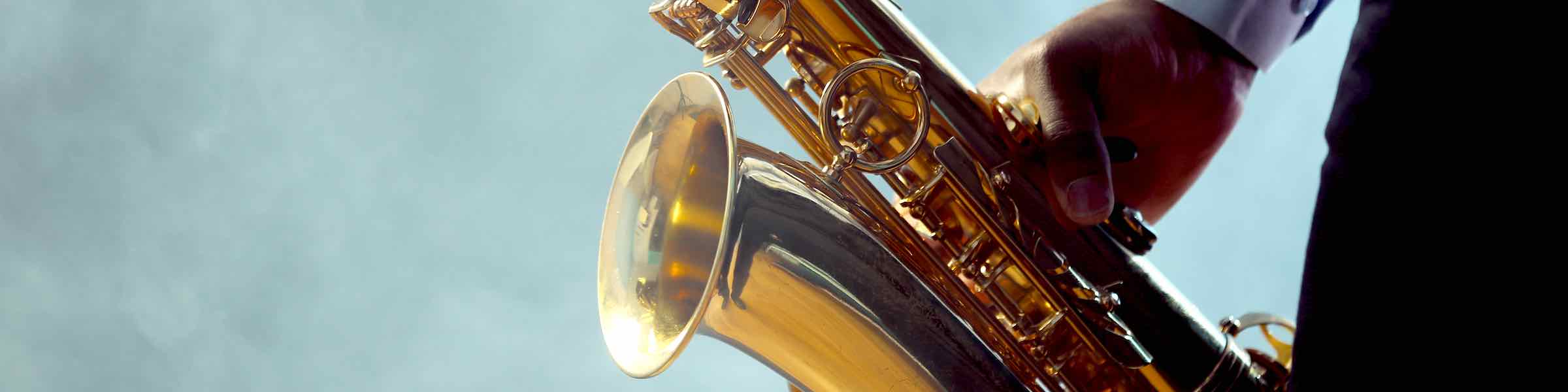 Close up view of a man playing a saxophone, with an abstract background.